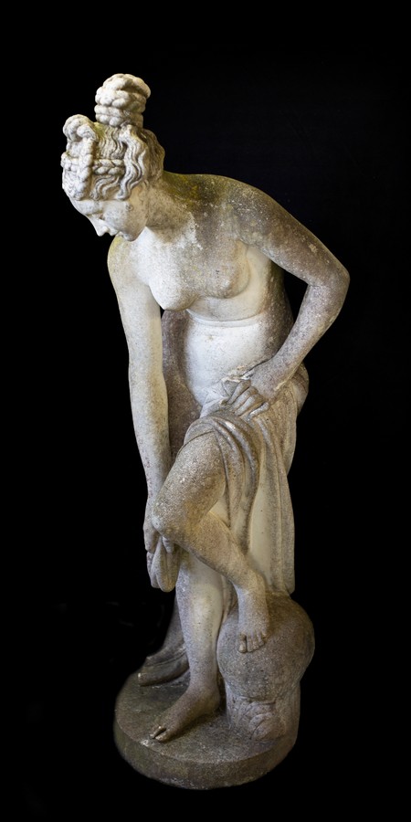 A reconstituted stone figure of a female bather,
