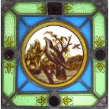 A stained glass panel, circa 1900, depicting a bird in song perched on a branch,