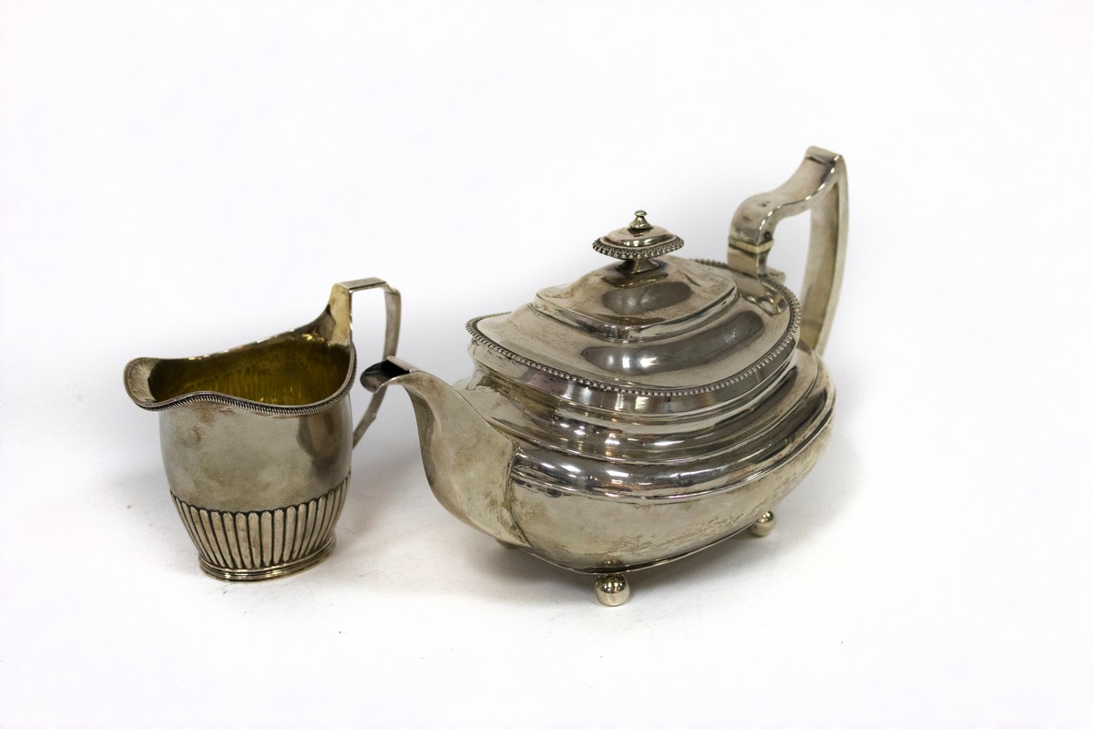 A George III silver teapot, SH, London 1815 and a cream jug with half-ribbed decoration,