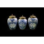 Three small Delft tobacco jars, late 18th Century, with brass covers,