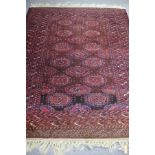 A Bokarah style rug of crimson ground, the central field with seventeen elephant foot medallions,