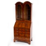 An 18th Century style walnut bureau bookcase, the twin arched top with two glazed doors,