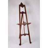 A large easel with adjustable picture rest and carved and foliate decoration,