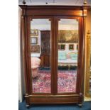 An Empire style parcel gilt wardrobe with gilt brass finials and breakfront cornice,