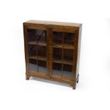 An oak bookcase enclosed by glazed panel doors,