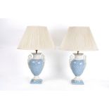 A pair of porcelain table lamps with blue and white feathered decoration and caryatid handles with