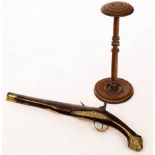 A brass mounted flintlock pistol and a turned and inlaid wig stand