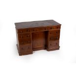 A mahogany kneehole desk fitted a surround of nine drawers and central recessed cupboard,