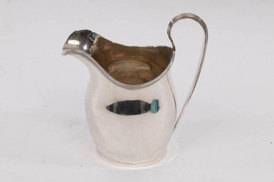 An Edwardian silver cream jug, Nathan & Hayes, Chester 1908, with reeded lip and loop handle,