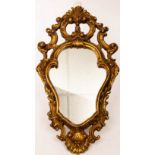 A gilt plaster Florentine style mirror, the cartouche shaped plate in a surround of C scrolls,