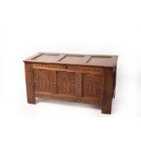 A 17th Century oak chest, the triple-panel hinged cover above the carved front,