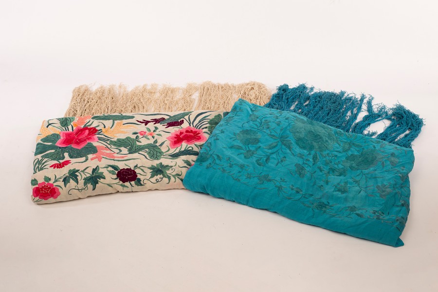 A Spanish finely embroidered shawl decorated all over flowers and another blue ground shawl