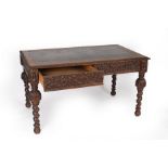 A Victorian oak writing table with inset writing surface, two frieze drawers and on carved,