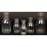 Five English 19th Century clear glass ring neck decanters, the tallest 21.