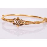 A 9ct yellow gold and seed pearl hinged bangle with central pearl set figure of eight,