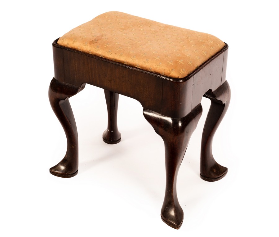 A late 17th/early 18th Century walnut stool with loose trap seat and shaped apron,