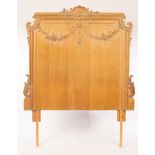 A carved oak headboard, the gadrooned crest rail centred by a shell motif above swags of flowers,