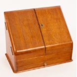 An oak stationery box with slope front and a fitted interior,