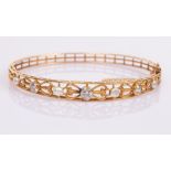 A 14k yellow gold hinged bangle set with three diamonds interspersed by pearls in a pierced