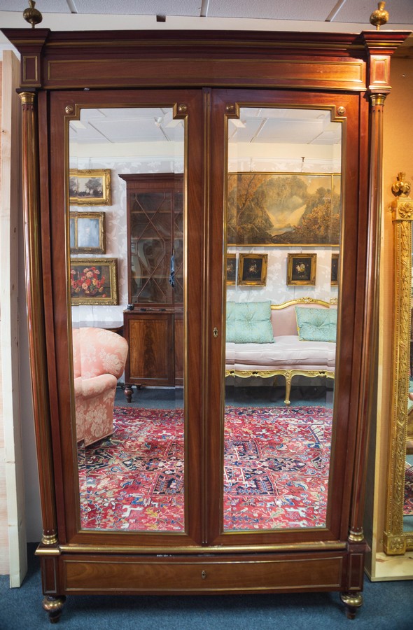 An Empire style parcel gilt wardrobe with gilt brass finials and breakfront cornice,