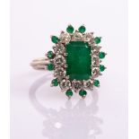 An emerald and diamond cluster ring, the central step cut emerald of approximately 2.