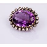 An amethyst and diamond brooch, the large oval amethyst to a surround of twenty diamonds,