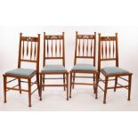 A set of four Art Nouveau oak dining chairs, with pierced crest rails and spindle backs,