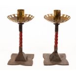 A pair of painted red wrought iron and brass candlesticks, attributable to William White,