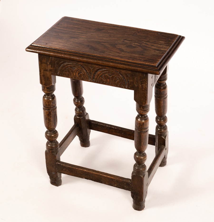A carved oak joint stool, on baluster turned legs united by square stretchers,