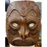 A large tribal mask with carved decoration and inset cowrie shell eyes,