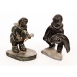 Two carved slate figures of Eskimos, one with a gong and beater, the other with a seal,