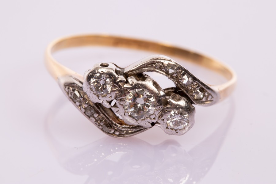 A three-stone diamond crossover ring, set in platinum and 18ct yellow gold,