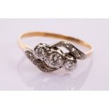 A three-stone diamond crossover ring, set in platinum and 18ct yellow gold,