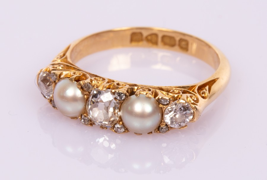 An Edwardian diamond and pearl ring in an 18ct yellow gold scroll setting with hallmarks for