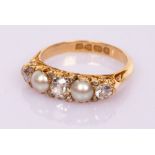 An Edwardian diamond and pearl ring in an 18ct yellow gold scroll setting with hallmarks for