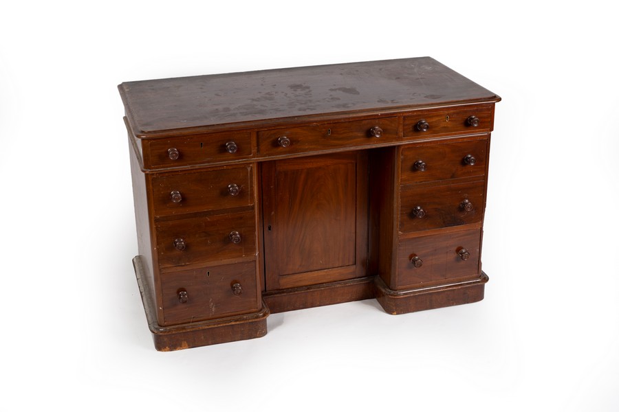 A mahogany kneehole desk fitted a surround of nine drawers and with a central recessed cupboard,