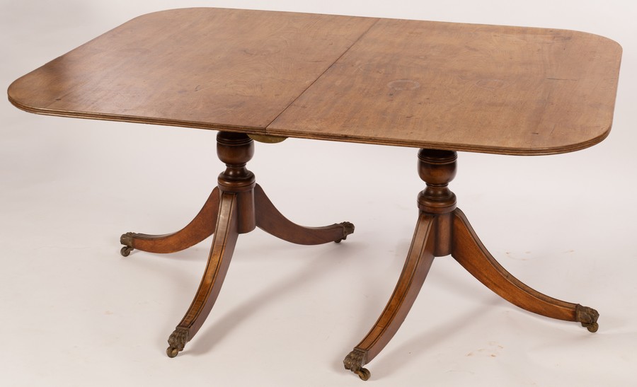 A George III mahogany twin-pedestal dining table, each pedestal of tripod form,