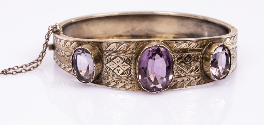 A silver gilt and amethyst hinged bangle, the three oval amethysts to an engraved silver bracelet,