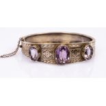 A silver gilt and amethyst hinged bangle, the three oval amethysts to an engraved silver bracelet,