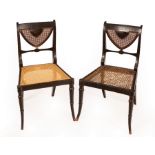 A pair of Regency ebonised single chairs with cane seats and backs and gilt painted arabesque
