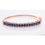 A sapphire and diamond hinged bangle, set in 14ct yellow gold, Italian assay mark,