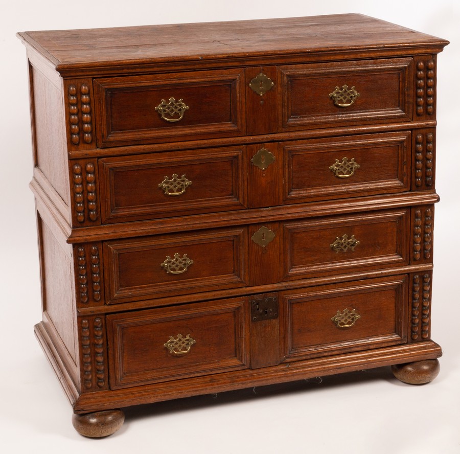 A 17th Century style oak chest of four long drawers, in two sections and on bun feet,