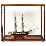 A model of a fully rigged two-masted gun boat in a glazed case,