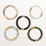 A group of jade or onyx and fourteen karat gold bangle bracelets