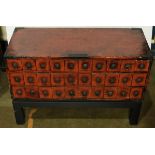 Small Chinese red lacquered thirty drawer apothecary chest on a modern ebonized stand