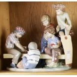 A Lladro porcelain sculpture of young boys playing cards on a bench