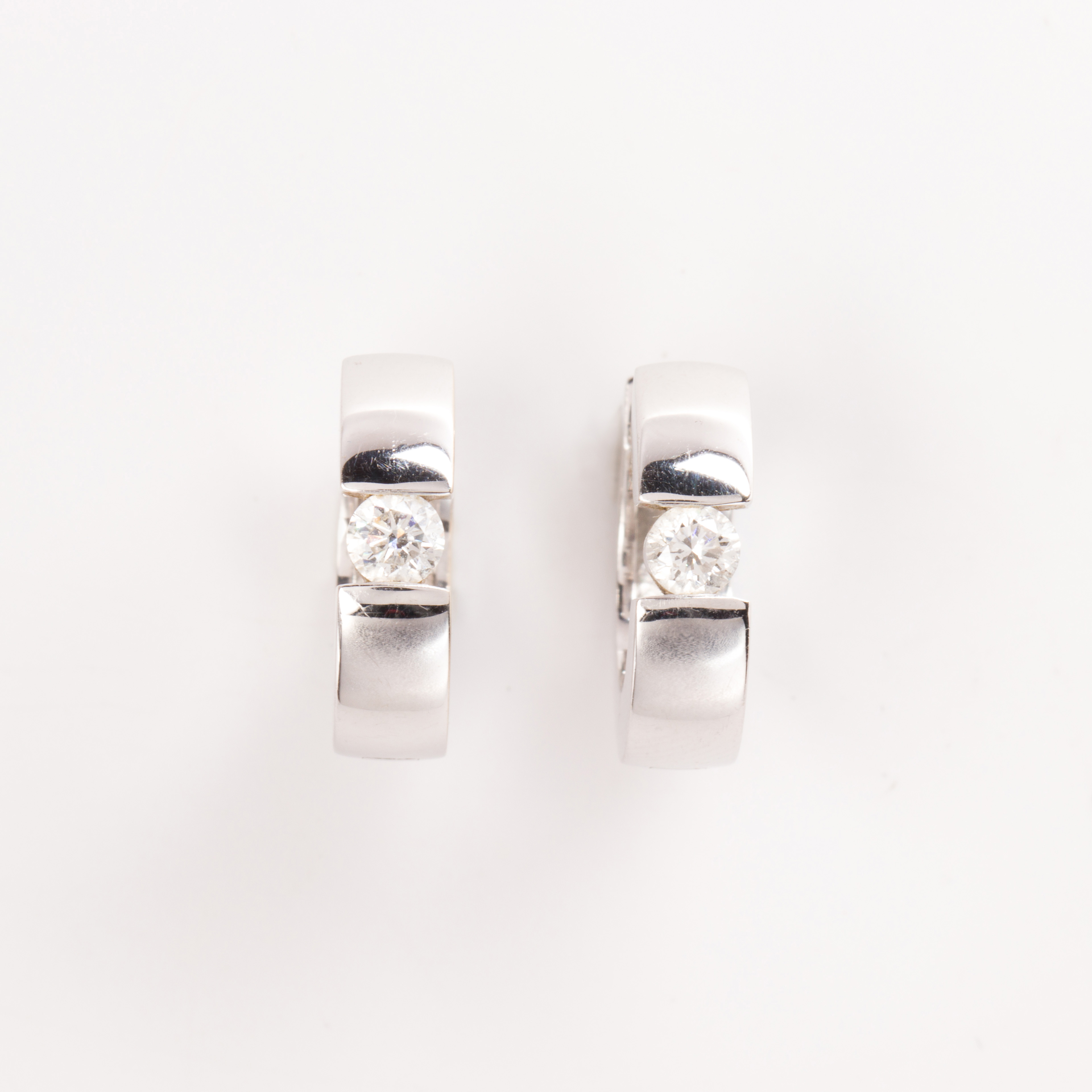 A pair of diamond and fourteen karat white gold huggie earrings