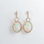A pair of opal, diamond and fourteen karat gold earrings