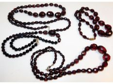 Four vintage faceted cherry amber style graduated beaded necklaces, 30in; 25in; 20; 19.5in long resp