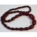 A vintage set of graduated cherry amber style beaded necklace, 23in long 48g, largest bead 27.2mm x
